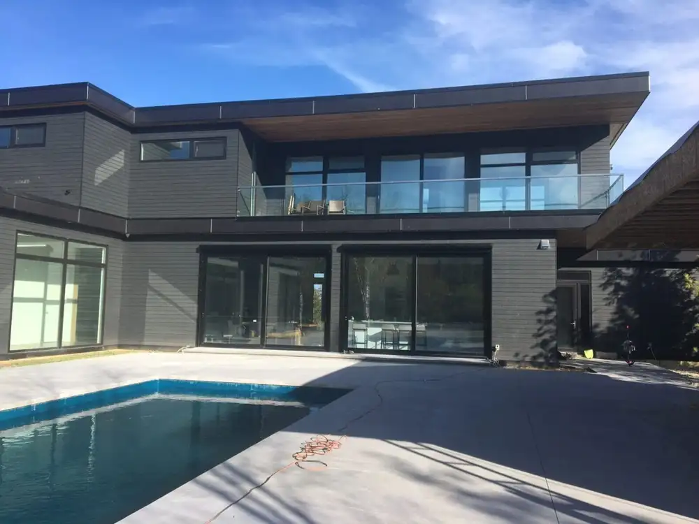 A large pool and patio area with a glass wall.