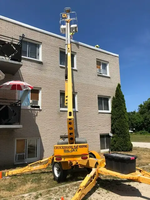 A crane is parked in front of a building.
