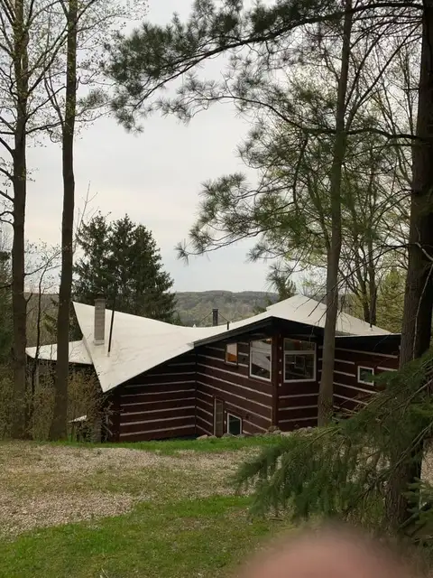 A log cabin in the woods with trees around it.